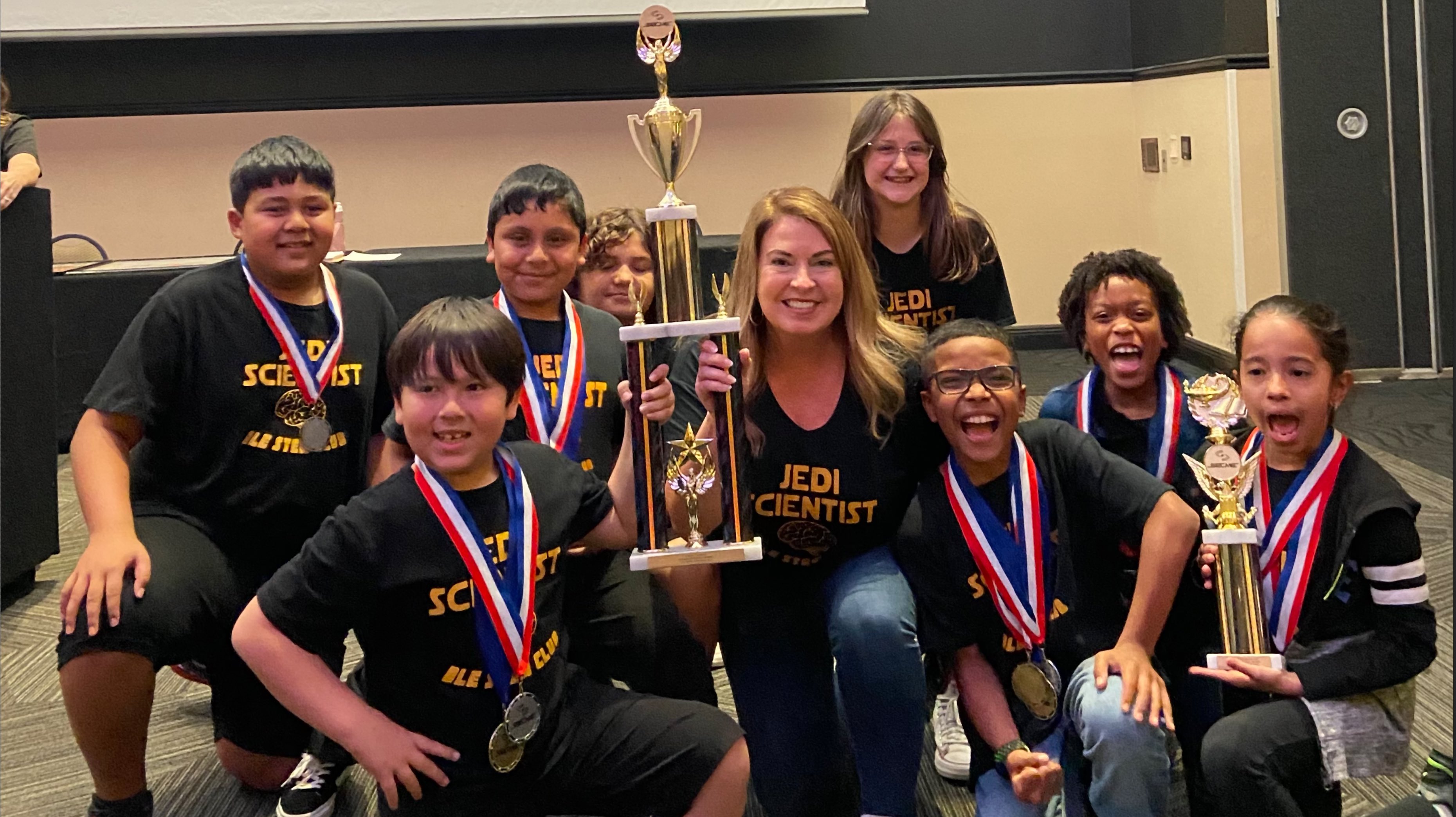 A group of people smile with a trophy