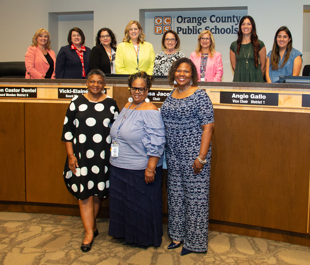 Three people pose in front of board dais