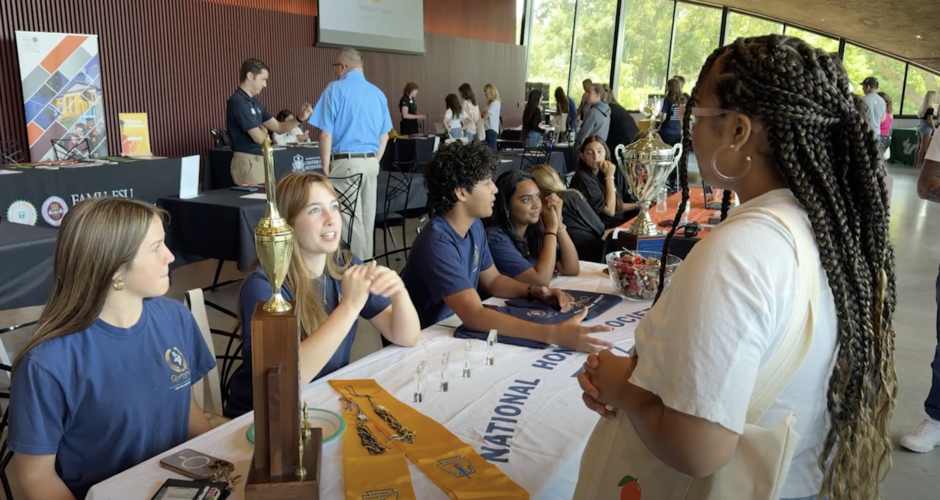 Two students at a table share information about NHS with another student