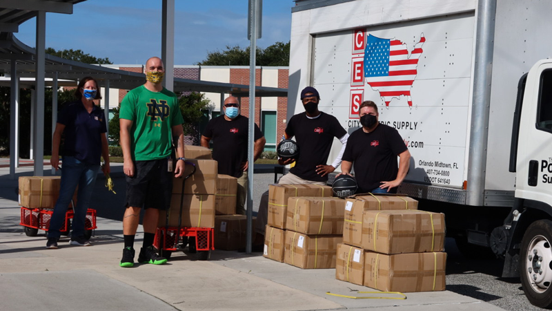 5 people unload boxes of basketballs