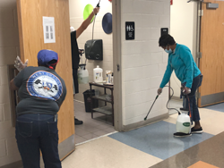 3 custodians sanitize a classroom