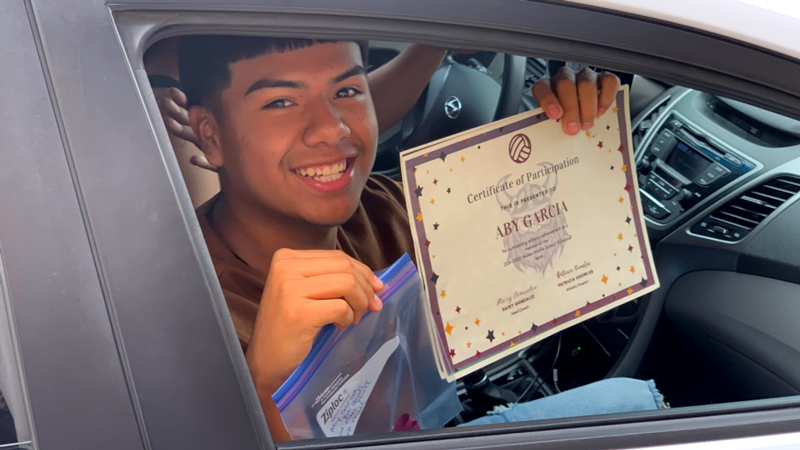 8th grader poses with participation certificate