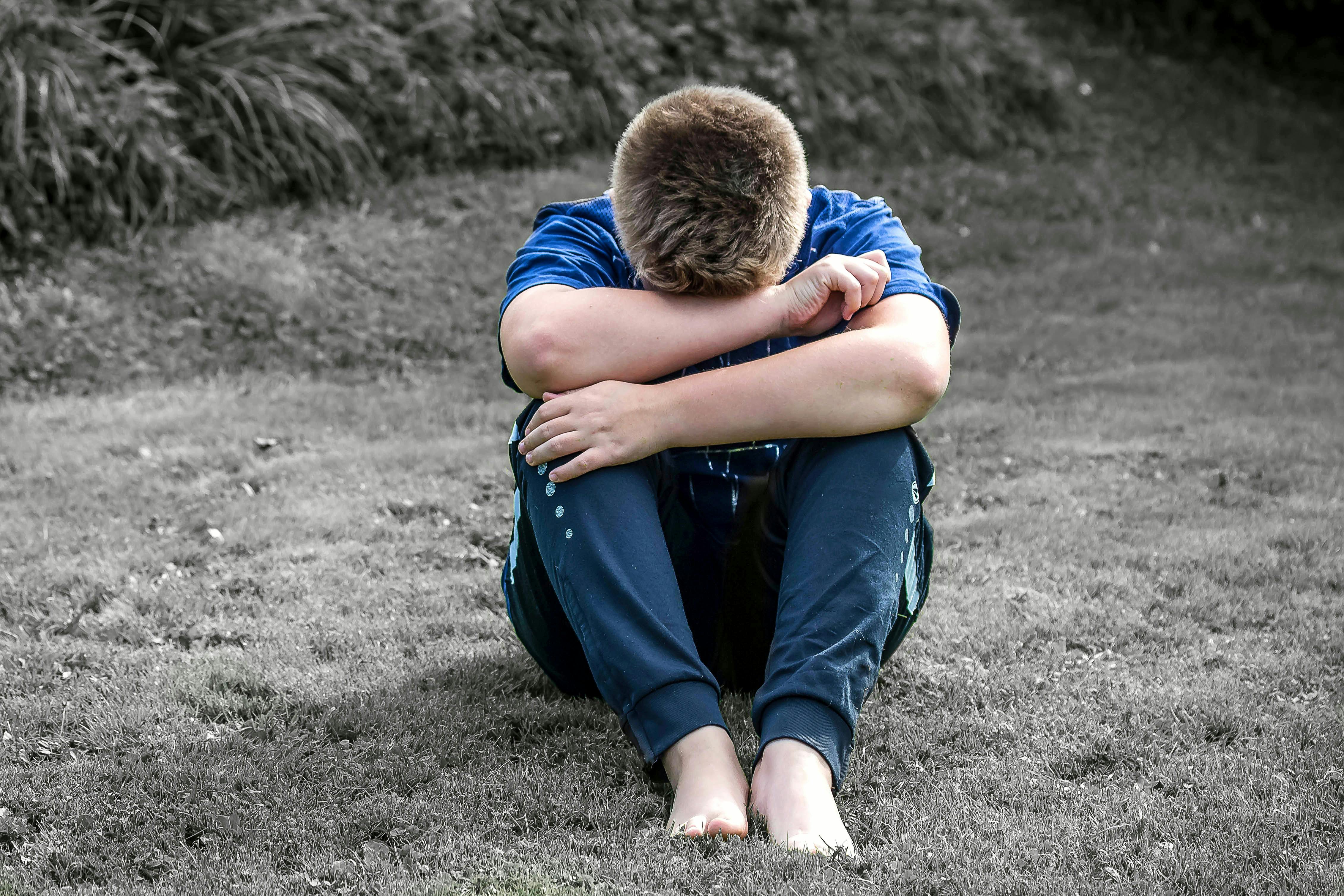 Sitting boy crying in field