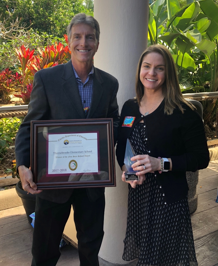 Mrs. Lentine receives honor at Sea World holding certificate with Mr. Daniels