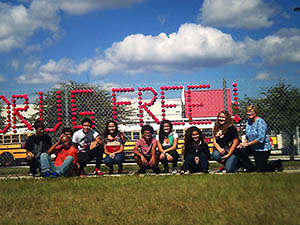 Photo of students sitting in front of a fence