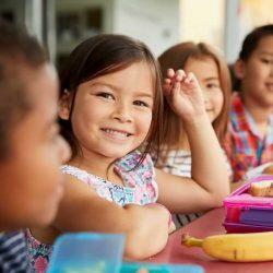 Little Girl Smiling While Sitting At Lunch Table