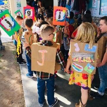 Kindergarten students with handmade alphabet vests 