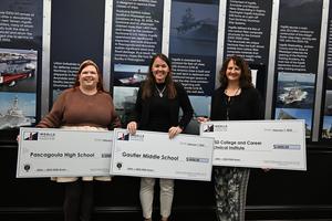 Jami Sheets, Peggy Pylate and Angela Ring hold their large checks from Ingalls Shipbuilding at the recipient breakfast
