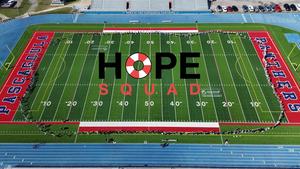 A drone shot above the Pascagoula High School football field showing hundreds of students holding up a paper chain link that circles the whole field