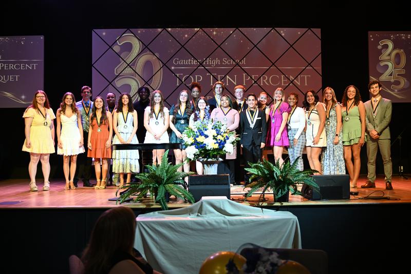 The top 10% of students all smile on stage while wearing medals.