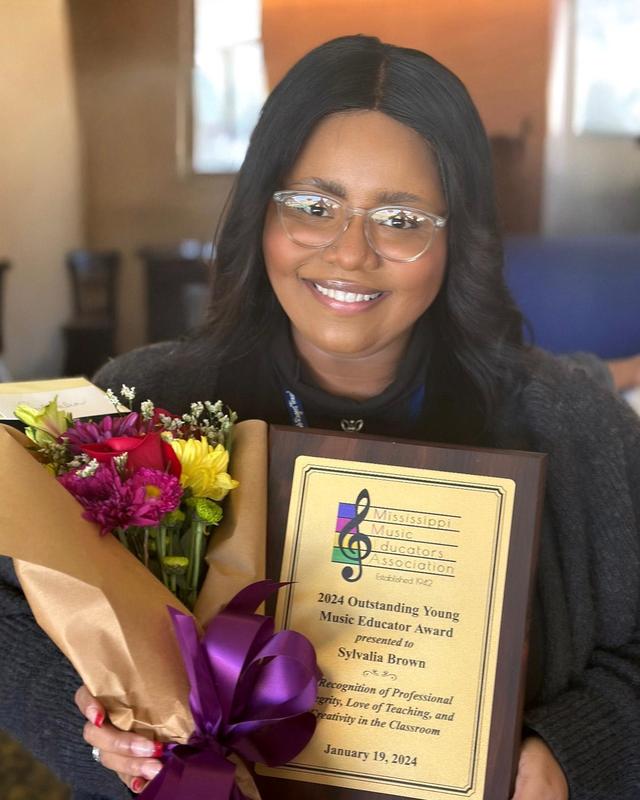 Sylvalia Brown smiles with her award and a bouquet of flowers