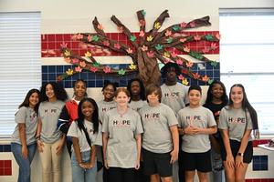 Hope Squad members stand together in front of 'Hope Tree' on wall at Colmer Middle School