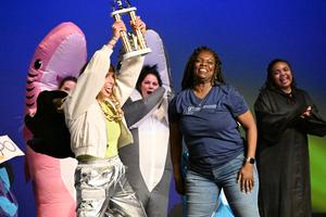 a woman dressed as a panther reveals her identity and cheers with a trophy in hand