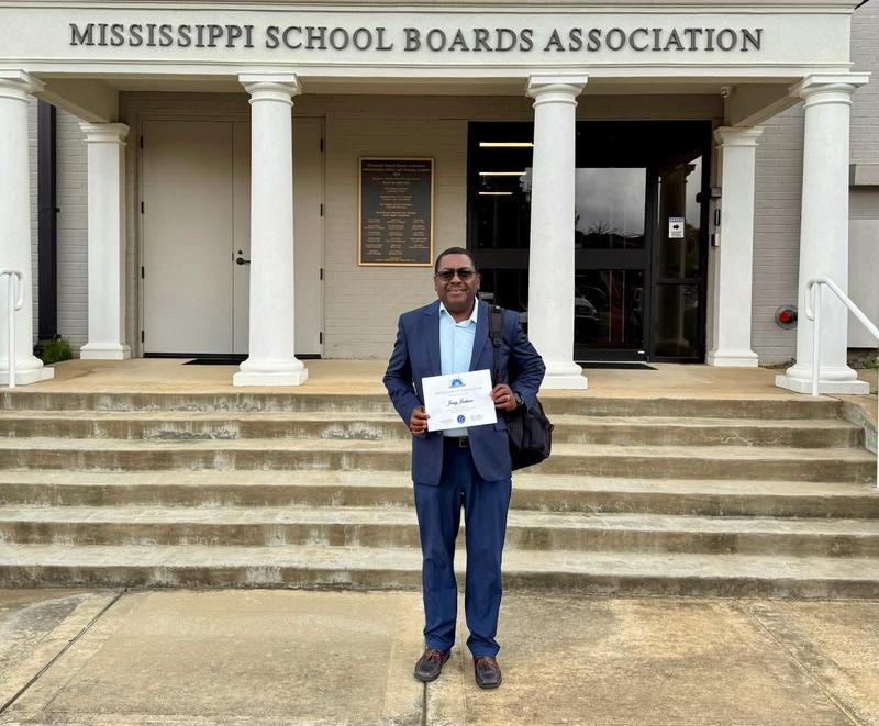 Jerry Jackson holds up his course completion certificate in front of the Mississippi School Boards Association building