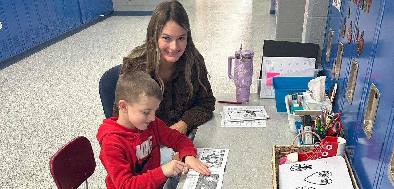 High School student helping an Elementary Student in the elementary hallway