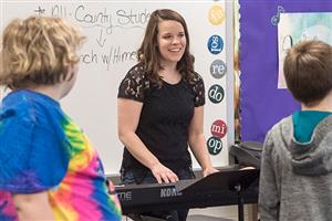 Mary Kay Himes plays the piano and leads children in singing 