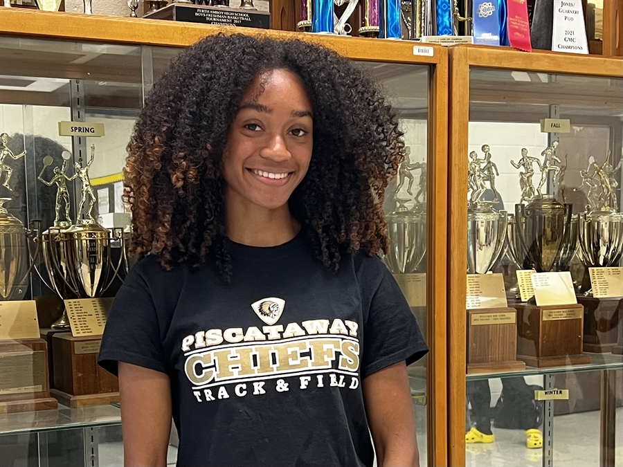 student in front of trophy case