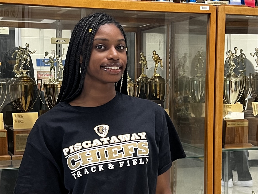 student in front of trophy case