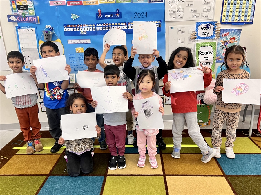 preschoolers holding drawings