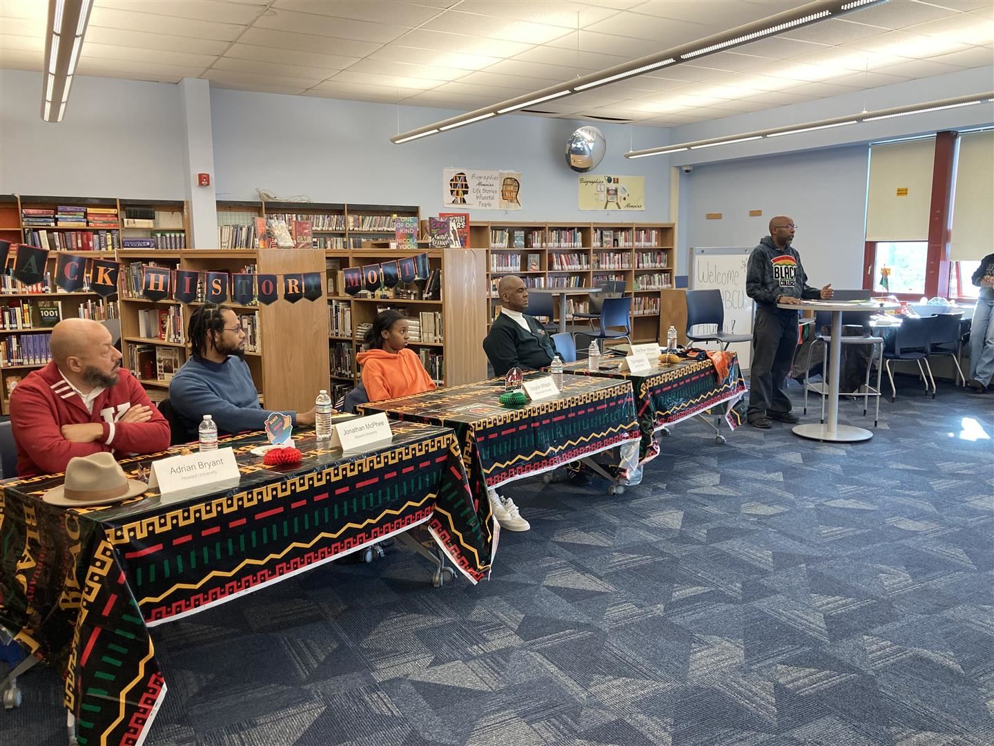  A panel of four people sit and listen to a keynote speaker