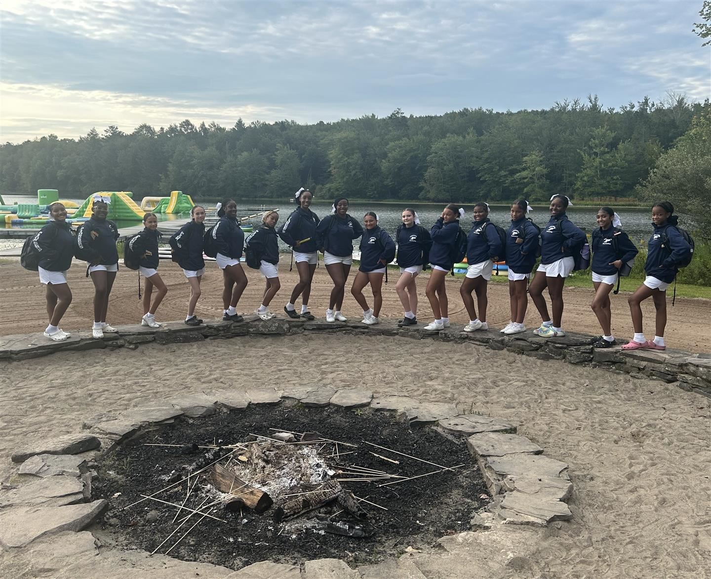 Poughkeepsie cheerleaders pose by an extinguished bonfire pit