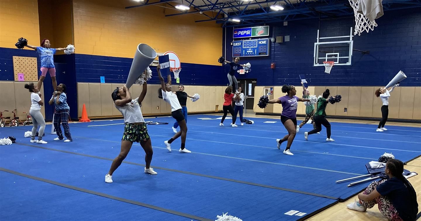 Cheerleaders practice in a gymnasium