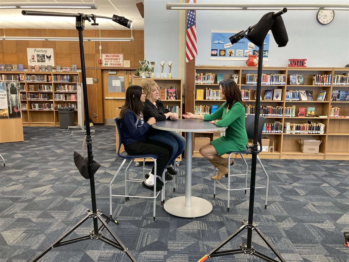 A student and teacher are interviewed on camera sitting at a table