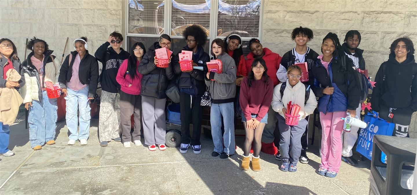  Sixteen students stand in a line outside holding valentines