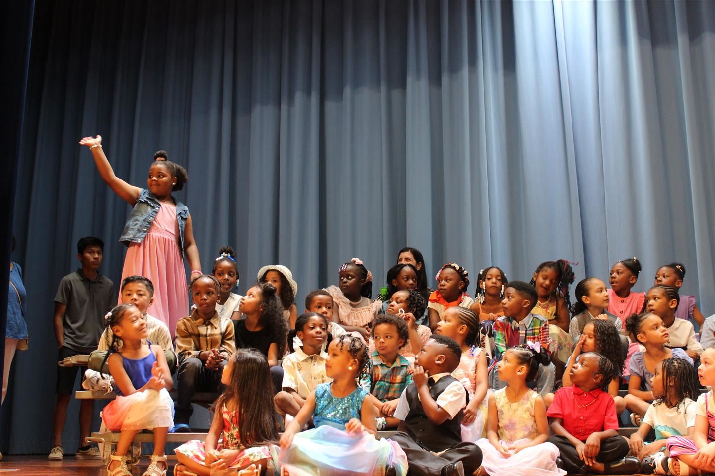 Students took turns standing on the risers and waving when their name was called.