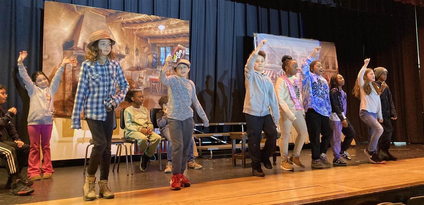  A line of students sing and march on stage
