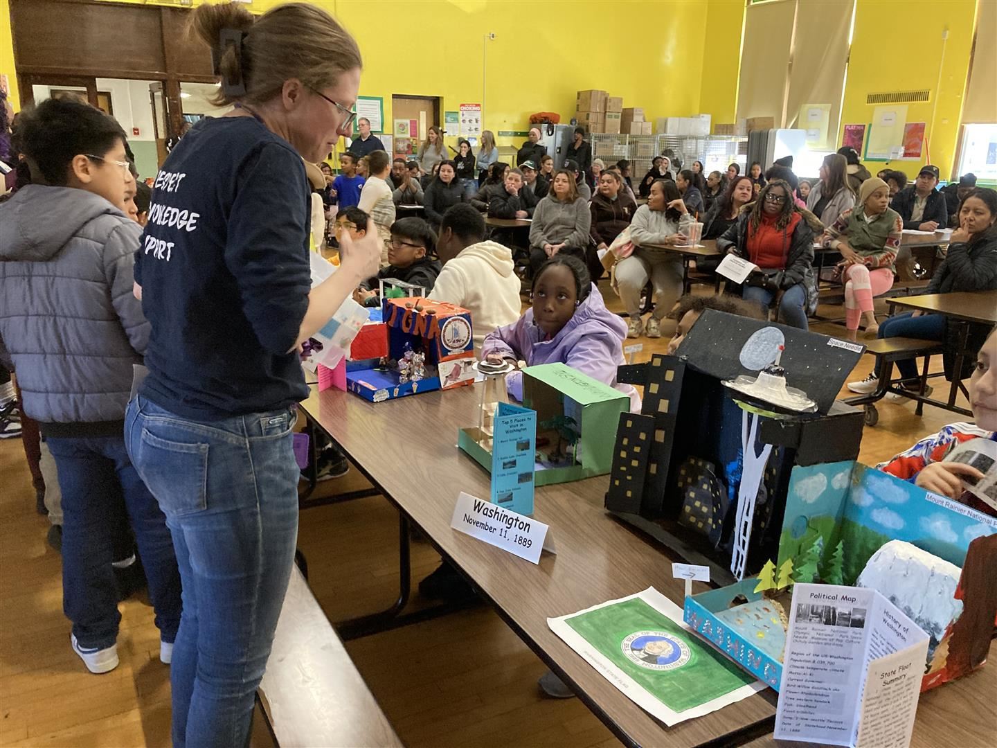 Librarian Dorothy Luongo talks to students about their state floats for Washington and Virginia
