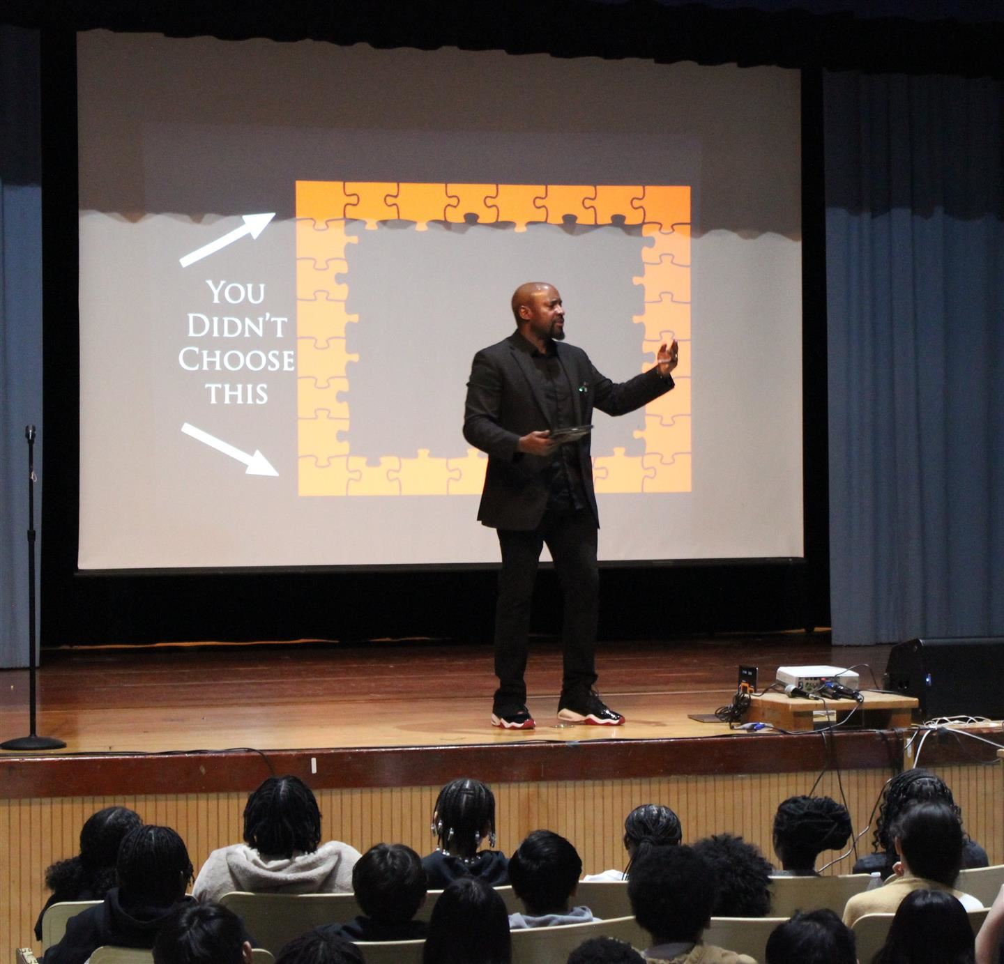  Mister Brown stands on stage and talks to students in the audience.