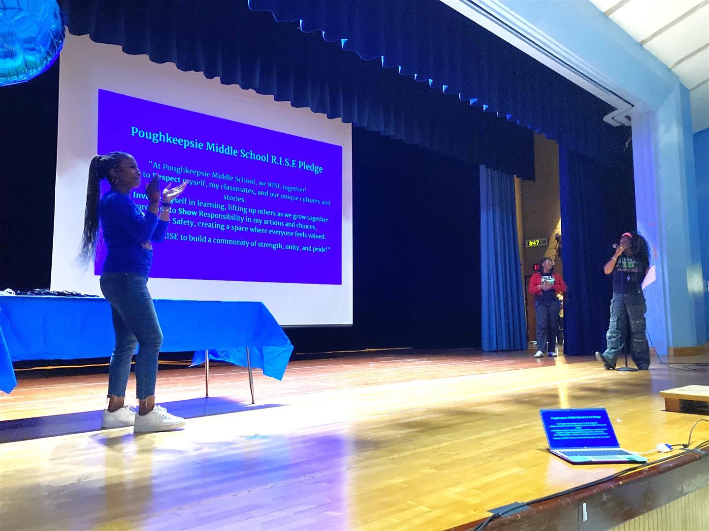 School leaders stand on a stage during a presentation