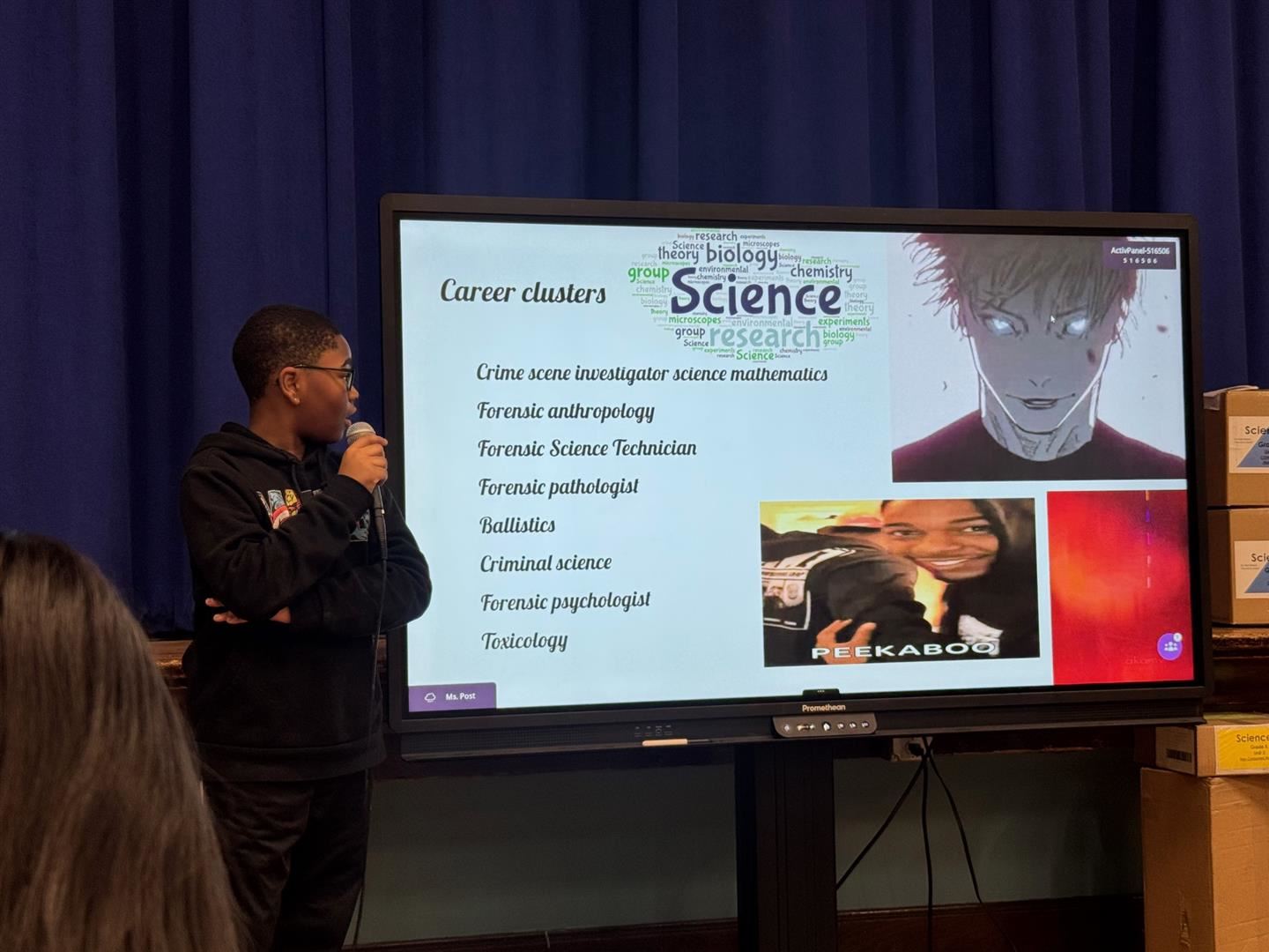  A student holds a microphone and reads off a presentation slide
