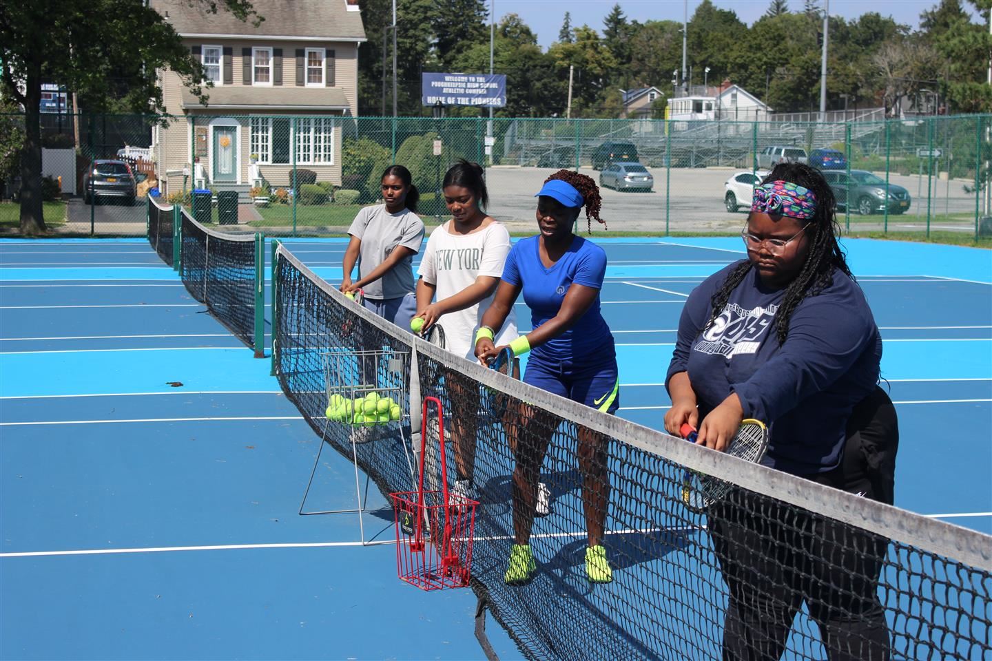  Girls tennis players and coach hit balls at the net
