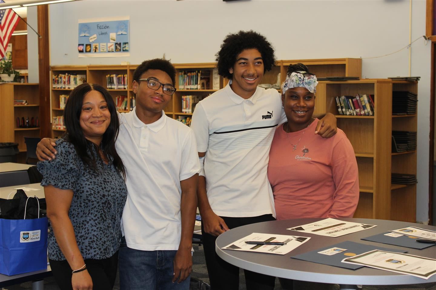 Two students pose for a photo with their moms
