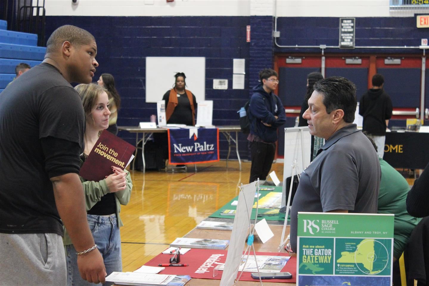 Students listen to a college rep at a table
