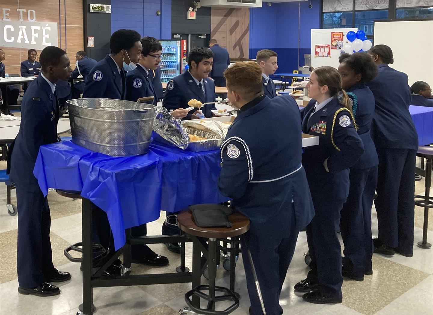 Cadets stand around a dessert table talking and eating