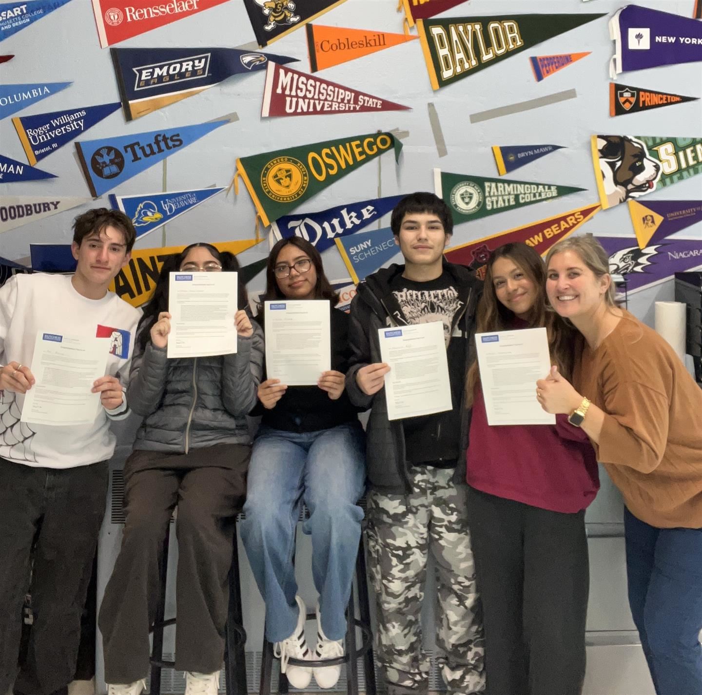 A counselor and five students pose with the students holding acceptance letters