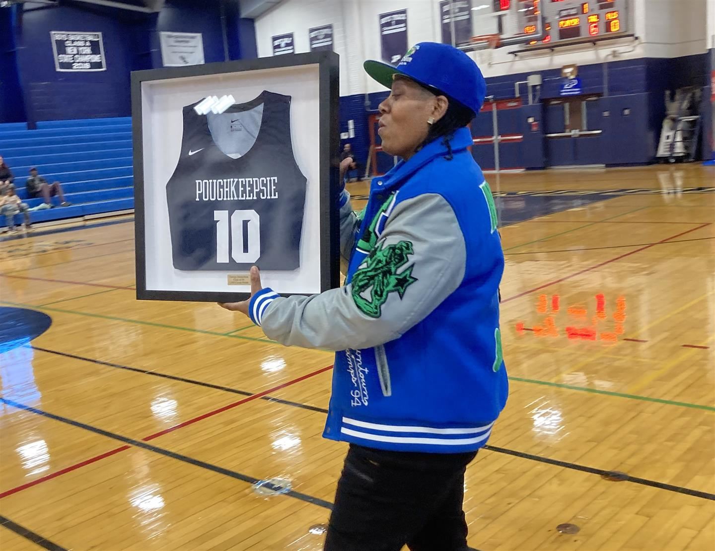 Terraya Richardson holds her framed jersey on the basketball court