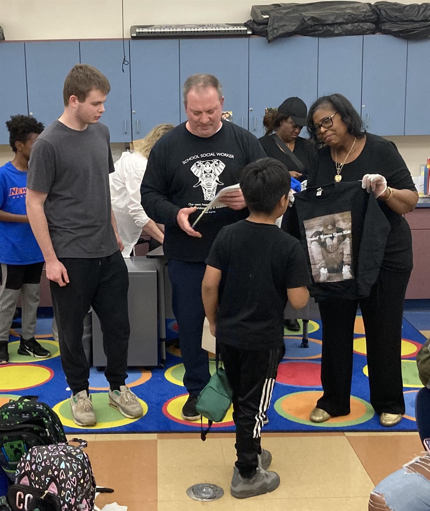 A boy receives a sweatshirt and certificate from three adults