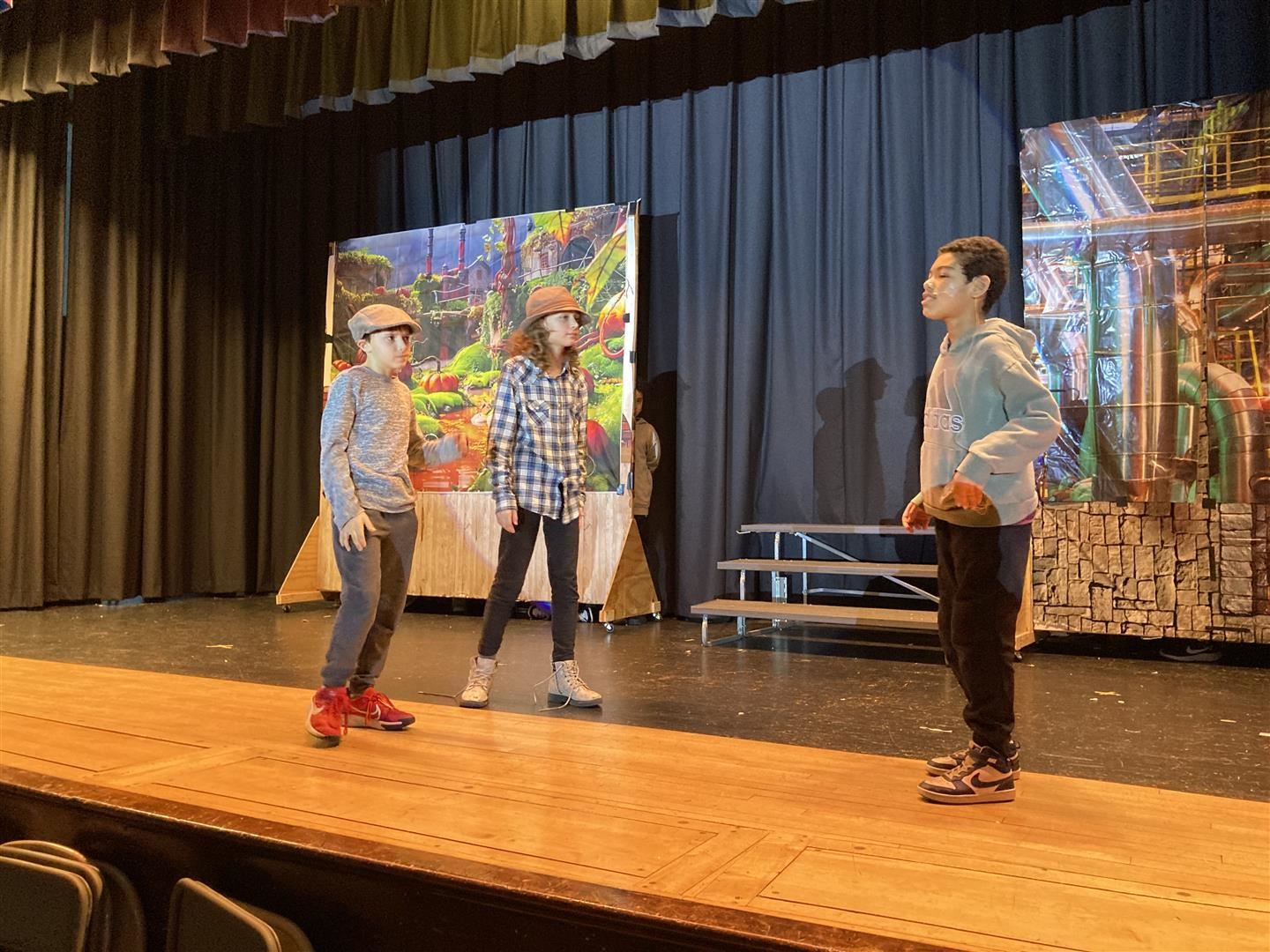 Three students rehearse a play on stage