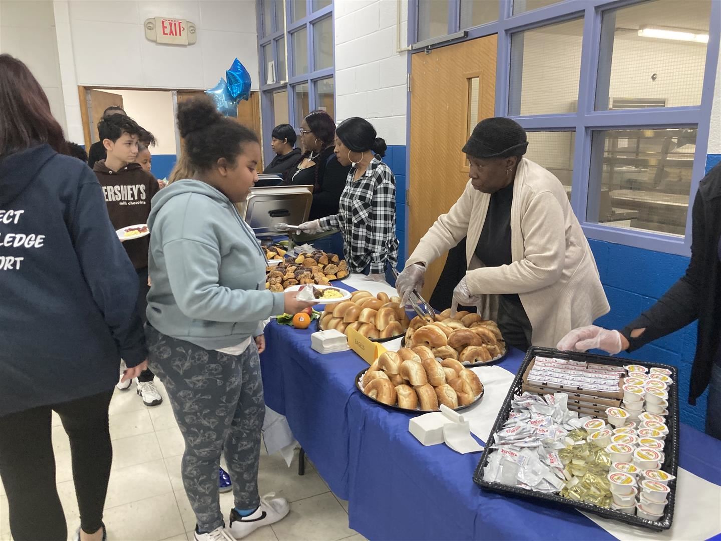 A student receives a bagel on a buffet line.