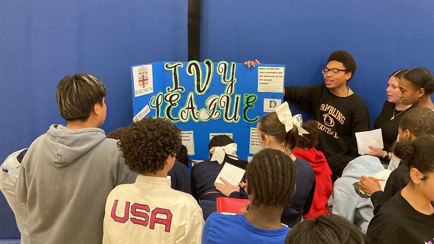  Students gather around a table with an older student discussing Ivy League schools.
