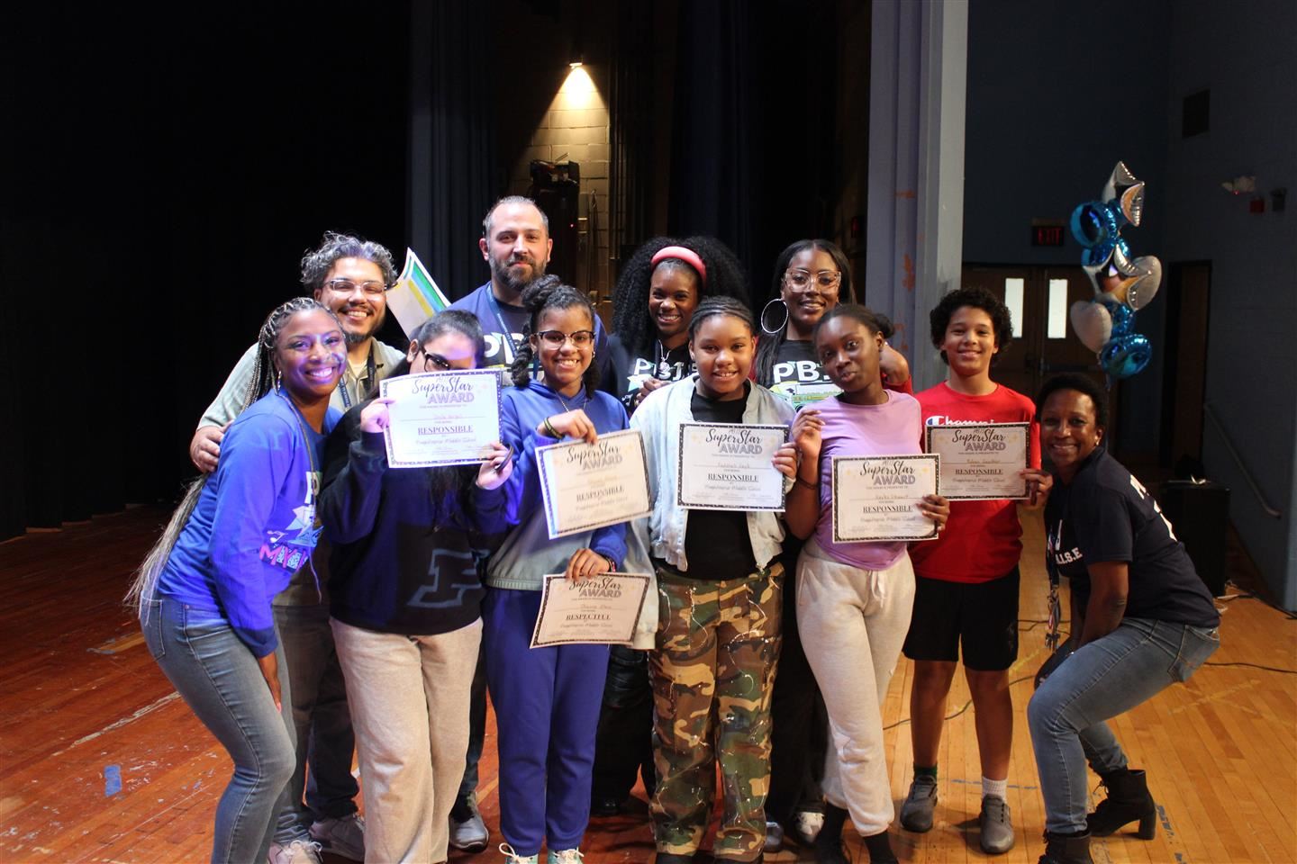 Students holding certificates and school leaders pose for a photo