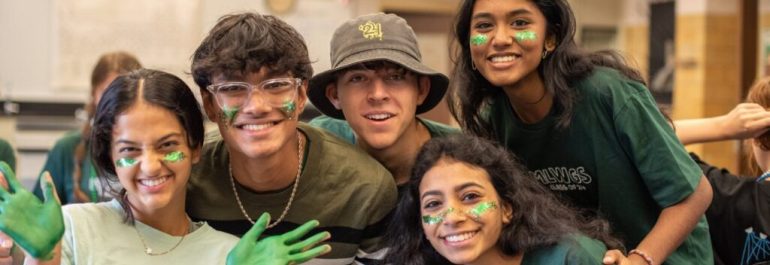 Group of MLWGS students smiling at the camera and wearing green during spirit week