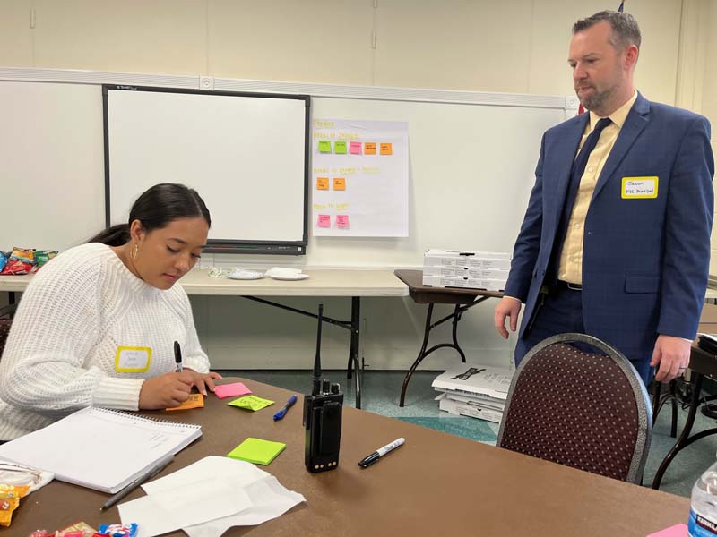 Two people in a meeting, one sitting and one standing