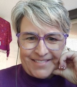 Caucasian woman with gray short hair and red shirt posing with a smile.