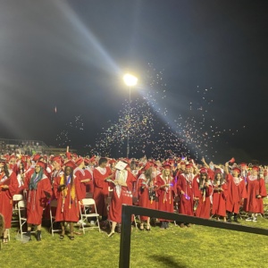SDPA Graduation 2023. Walden Grove School. Student walking in their red graduation gown with SPDA students.
