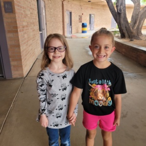 SDPA students in person testing. Two caucasions girls holding hands and smiling for the camera.